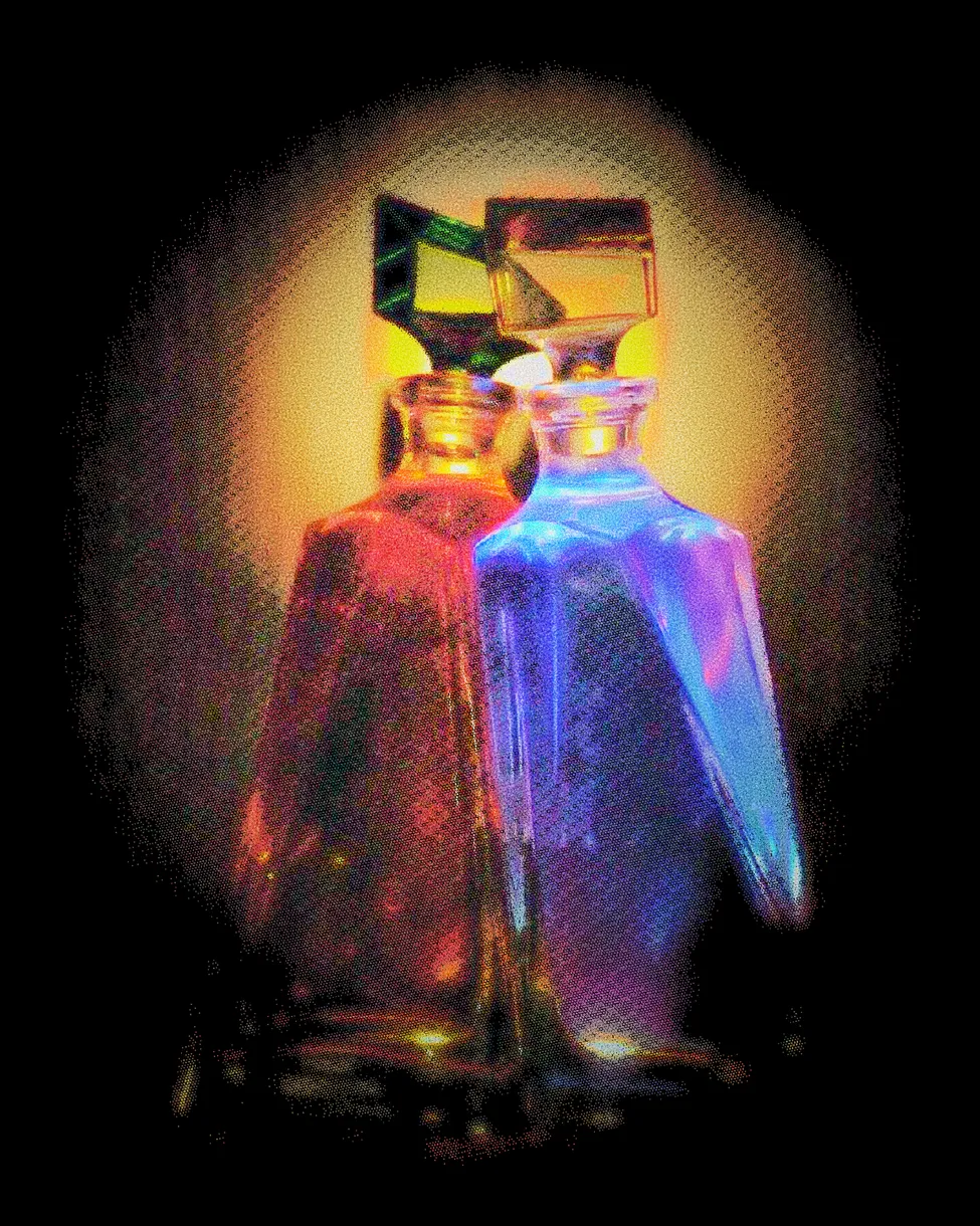 Two glass bottles, one red and one blue, lit gold from behind